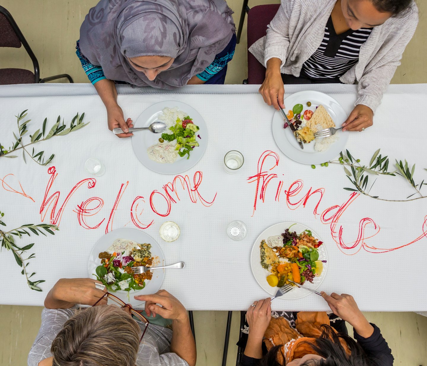 Four diverse women enjoy a meal together at a table.