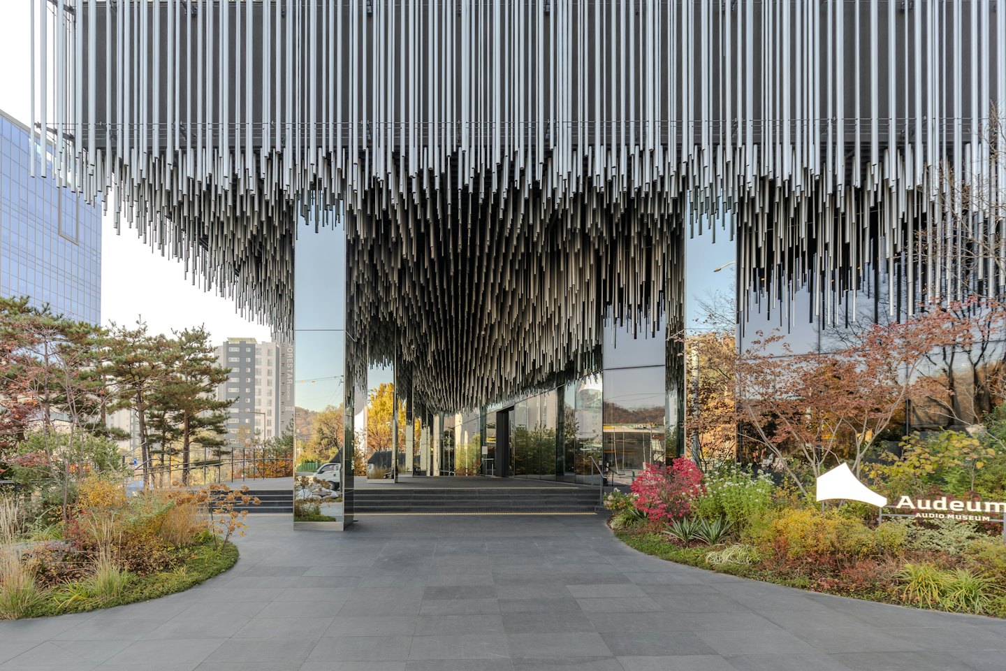 Modern building entrance with reflective glass and autumn landscaping.