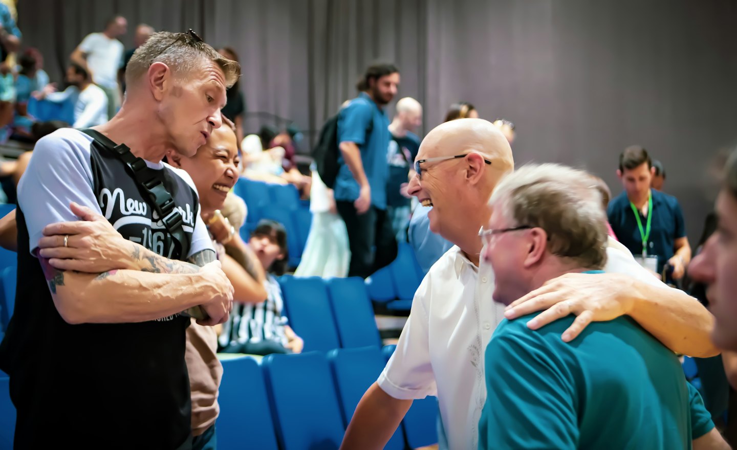 Professionals laugh and converse together during an indoor business event.
