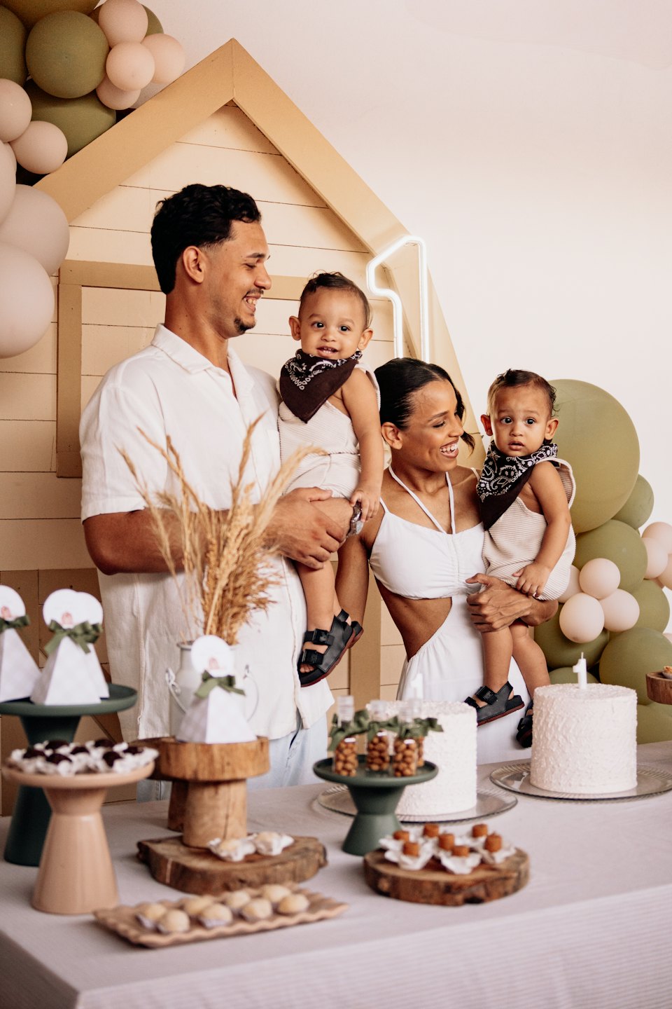 Parents hold their twin babies at a first birthday party.