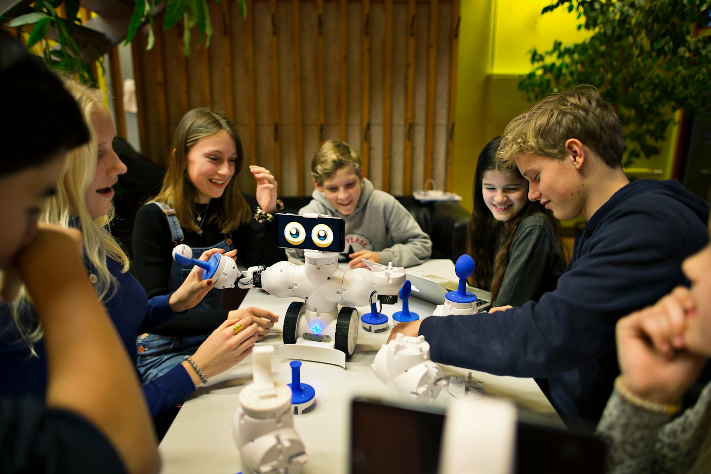 Teenagers collaborating on a robot project at a table.